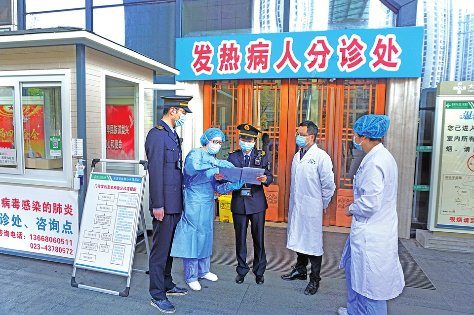 李琴(中)在发热病人分诊处检查入院分诊记录
